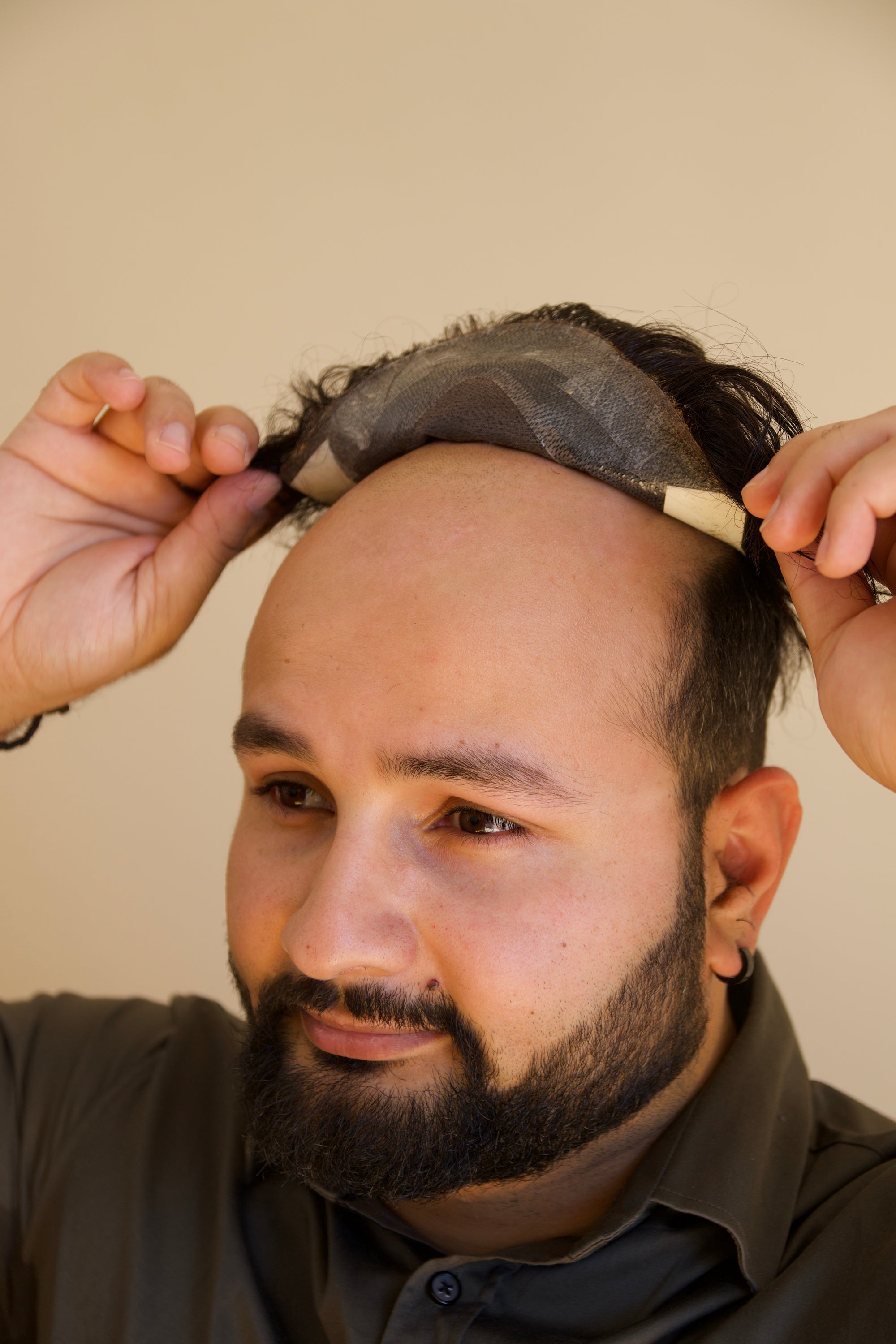 Man putting on hair toupee by himself